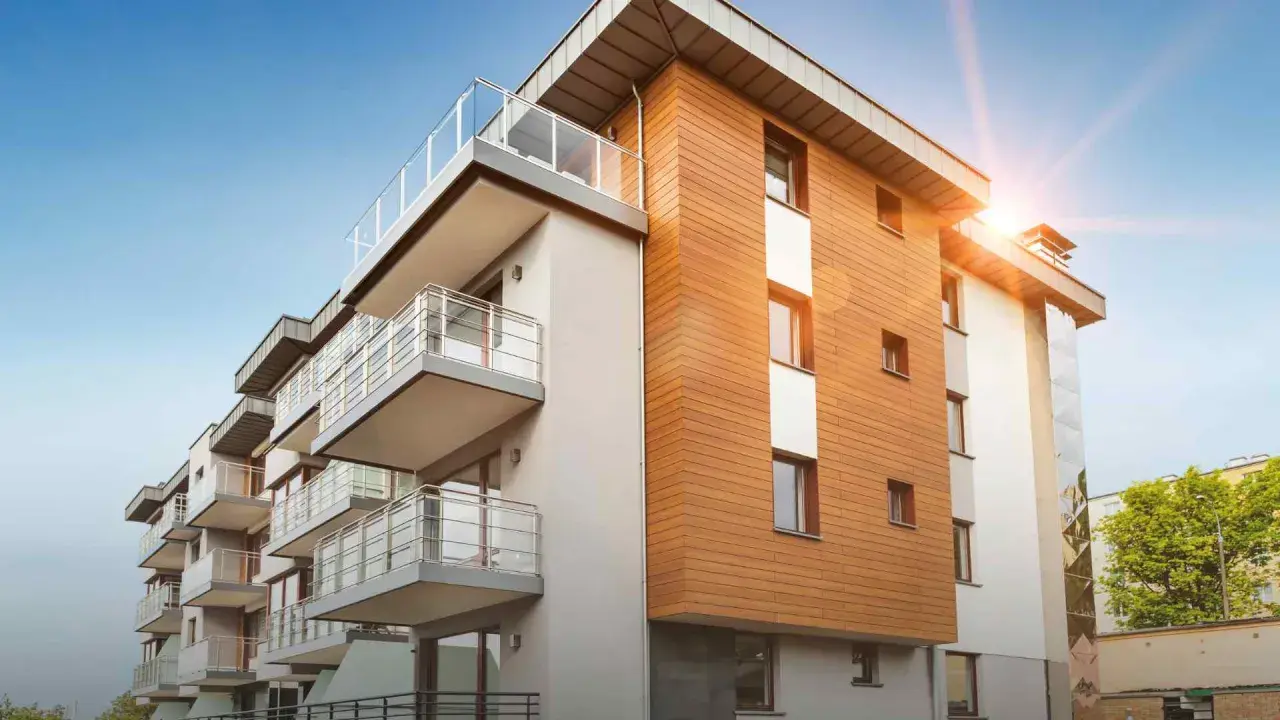 Modernt bostadshus med träfasad och balkonger. Solen skiner, en bild av trygghet och ansvarsfrihet för styrelse.