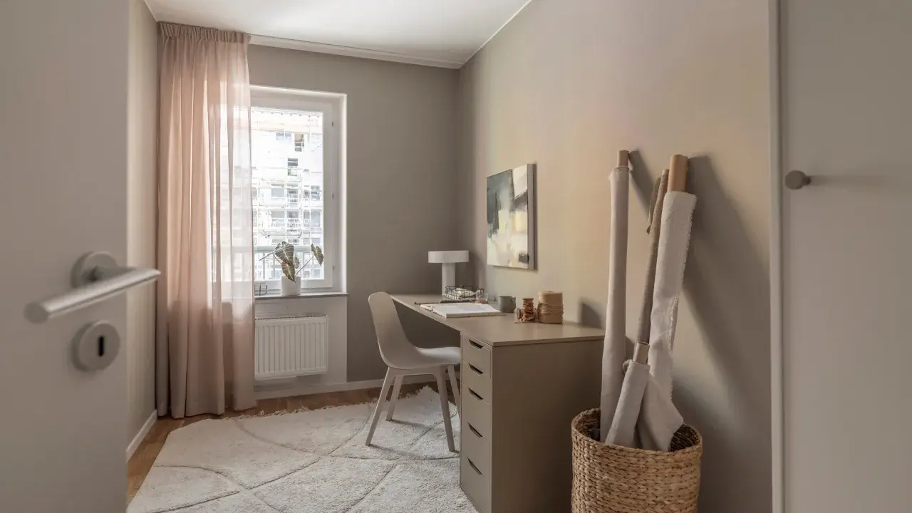 Mysigt hemmakontor med skrivbord, stol, lampa och tygrullar. Perfekt hemmakontor inspiration för kreativa själar.
