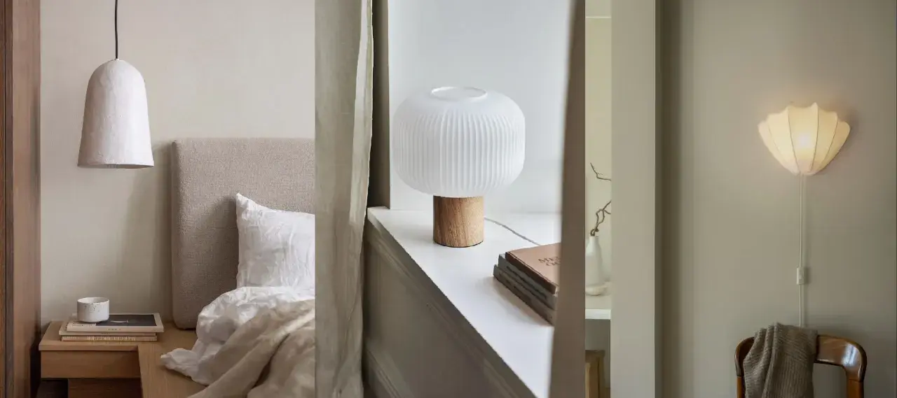 Sovrumsinspiration med en taklampa i papper, en bordslampa med träfot och en vägglampa som liknar ett skal.