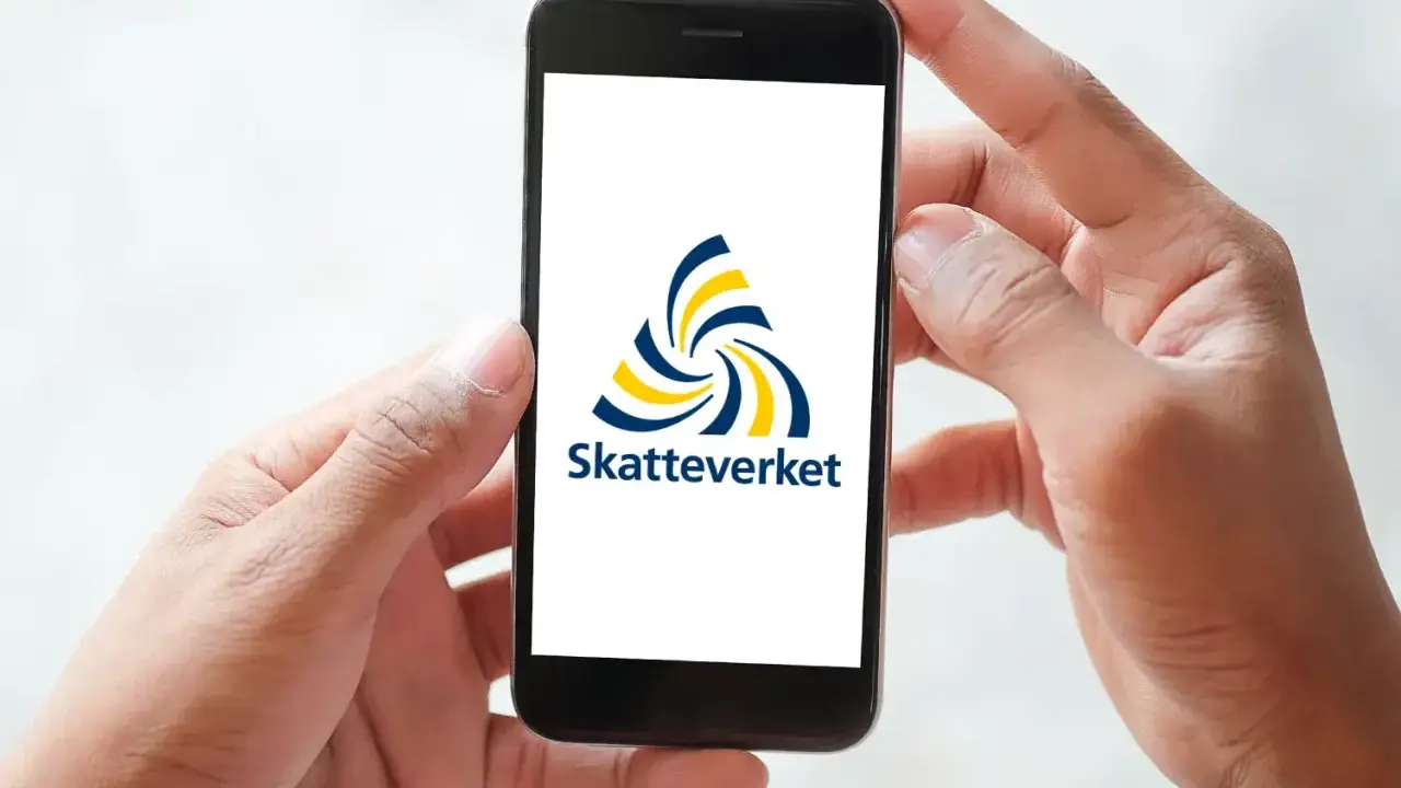 Händer håller en mobil med Skatteverkets logotyp. Enkel hantering av fastighetsskatt deklaration.