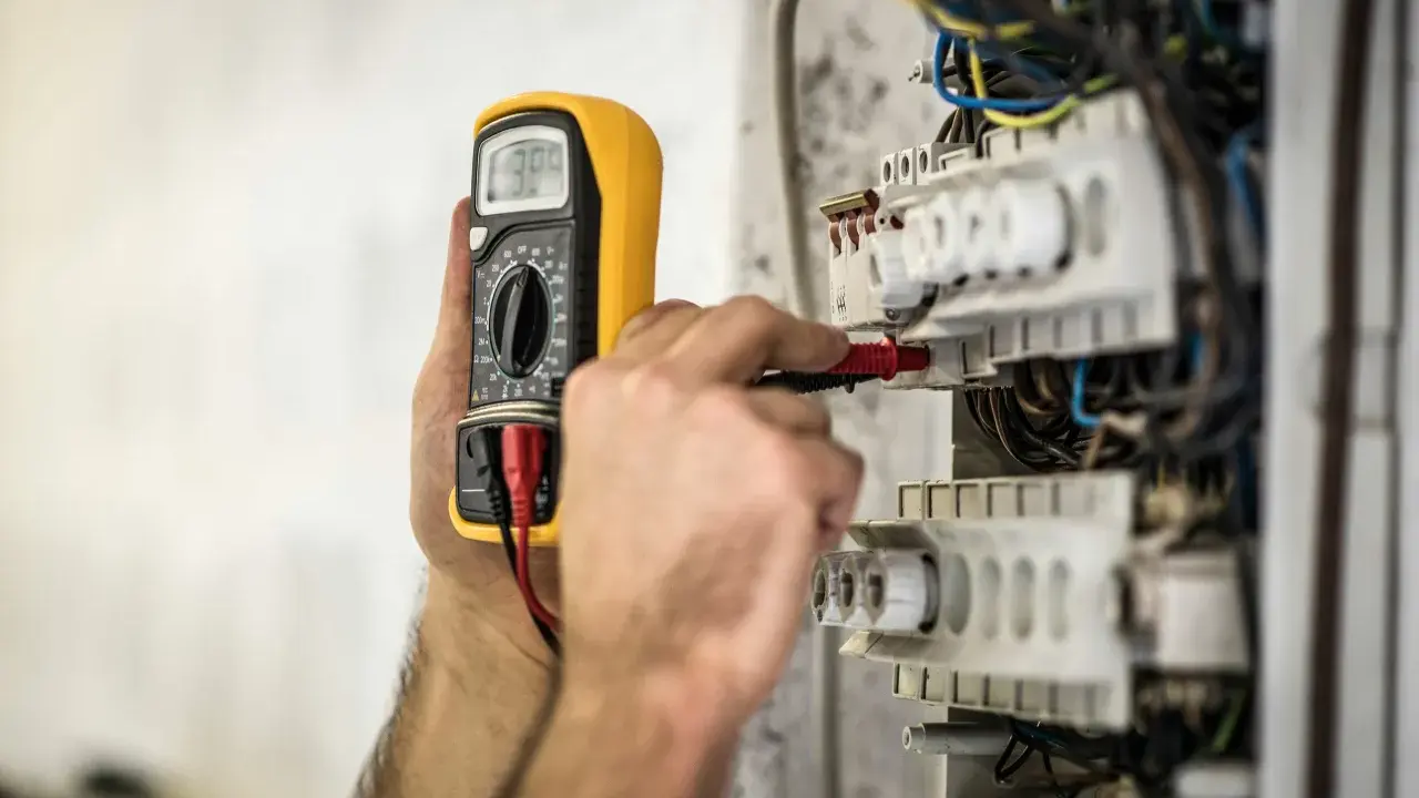 En elektriker använder en multimeter för att kontrollera elsystemet. Detta är en del av elbesiktning krav för säkerhet.