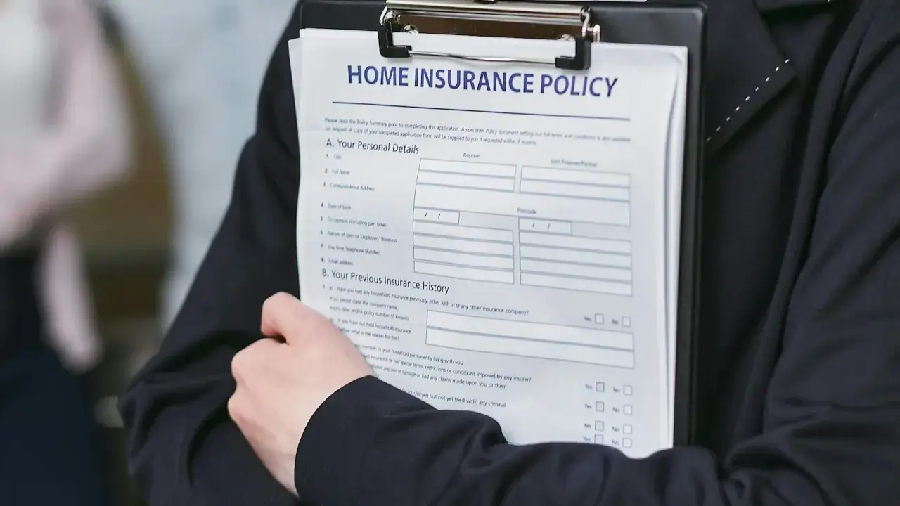 Person håller ett dokument med rubriken "HOME INSURANCE POLICY". Detta kan vara en del av ett hyresavtal lokal.