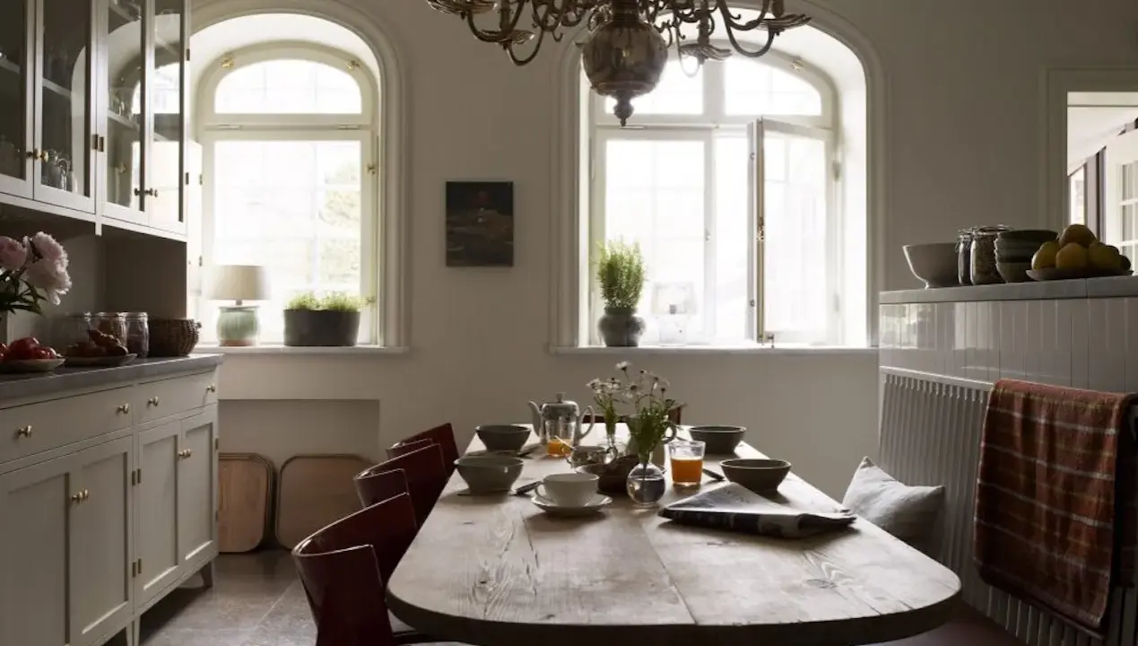 Rustik matplats med träbord, röda stolar och en bänk. Vackra fönster och skåp ger inspiration för inredningstips.