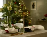 Vacker julpynt inspiration med dukat bord, amaryllis och julgran i bakgrunden. Ljusen skapar en mysig stämning.