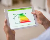 En person håller en surfplatta som visar en energideklaration för en bostadsrättsförening (brf) med en skala från A till G.