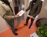 En mäklare ger en broschyr om bostäder till en kund. Kanske handlar det om en kontantinsats på 5 procent.