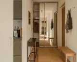 En ljus hall med spegelskjutdörrar, en smal konsol och en träbänk. Perfekt hall inspiration för en funktionell och stilren entré.