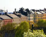 Färgglada husfasader i stadsmiljö, med träd i förgrunden. En vy som kan ge en känsla av belåning per kvadratmeter i en levande stad.