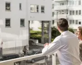 Ett par njuter av utsikten från sin balkong, kanske funderar på framtida medlemsinsatser brf.