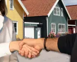 Handslag framför färgglada hus. Kanske en affär som gör det möjligt att **låna till handpenning** för drömhuset.