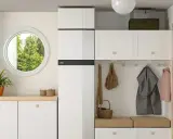 Hall med vit inredning, en NIBE F735 värmepump, fönster, trappa och klädkrok.