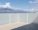 Frosted glass privacy screens on a tiled patio with a view of mountains and the sea.