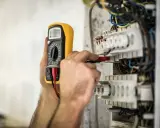 En elektriker använder en multimeter för att kontrollera elsystemet. Detta är en del av elbesiktning krav för säkerhet.