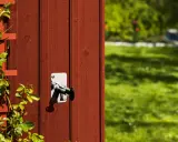 Ny vattenutkastare monterad på rött trä. En klätterväxt slingrar sig på vänster sida.