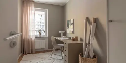 Mysigt hemmakontor med skrivbord, stol, lampa och tygrullar. Perfekt hemmakontor inspiration för kreativa själar.