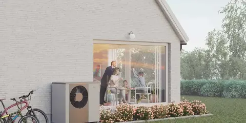 En familj njuter av en solig dag vid sitt hus, med en NIBE S2125-12 värmepump som diskret står vid sidan.