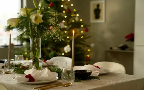 Vacker julpynt inspiration med dukat bord, amaryllis och julgran i bakgrunden. Ljusen skapar en mysig stämning.