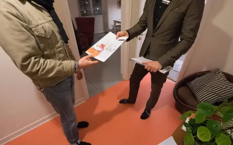 En mäklare ger en broschyr om bostäder till en kund. Kanske handlar det om en kontantinsats på 5 procent.