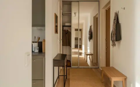 En ljus hall med spegelskjutdörrar, en smal konsol och en träbänk. Perfekt hall inspiration för en funktionell och stilren entré.