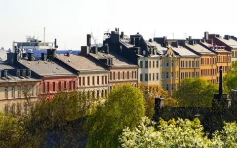Färgglada husfasader i stadsmiljö, med träd i förgrunden. En vy som kan ge en känsla av belåning per kvadratmeter i en levande stad.