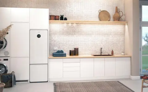 Vit tvättstuga med Bosch Compress 7800i värmepump, tvättmaskin, torktumlare och en bänkskiva med diskho.