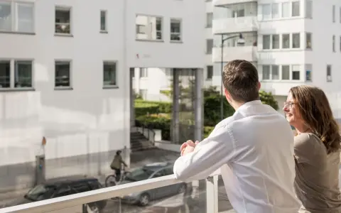 Ett par njuter av utsikten från sin balkong, kanske funderar på framtida medlemsinsatser brf.