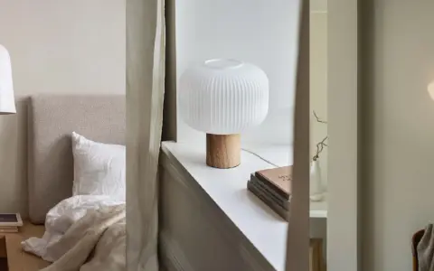 Sovrumsinspiration med en taklampa i papper, en bordslampa med träfot och en vägglampa som liknar ett skal.