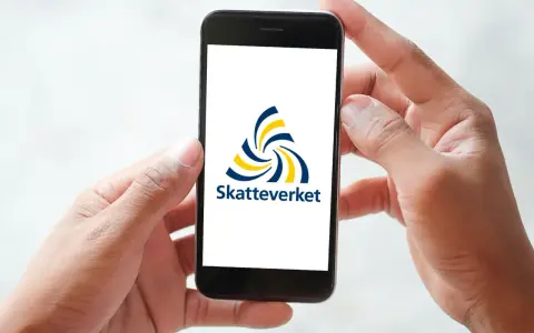 Händer håller en mobil med Skatteverkets logotyp. Enkel hantering av fastighetsskatt deklaration.