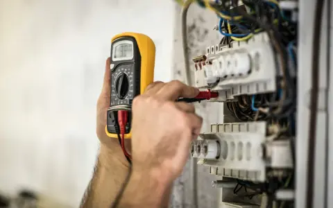 En elektriker använder en multimeter för att kontrollera elsystemet. Detta är en del av elbesiktning krav för säkerhet.