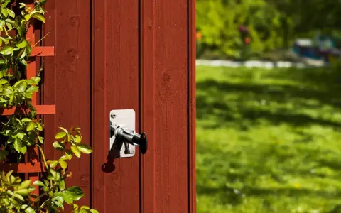 Ny vattenutkastare monterad på rött trä. En klätterväxt slingrar sig på vänster sida.