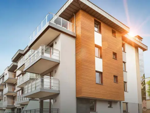 Modernt bostadshus med träfasad och balkonger. Solen skiner, en bild av trygghet och ansvarsfrihet för styrelse.