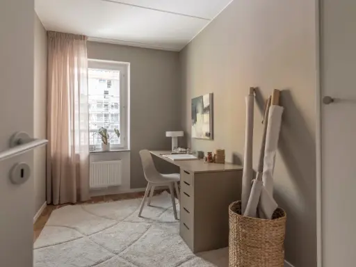 Mysigt hemmakontor med skrivbord, stol, lampa och tygrullar. Perfekt hemmakontor inspiration för kreativa själar.