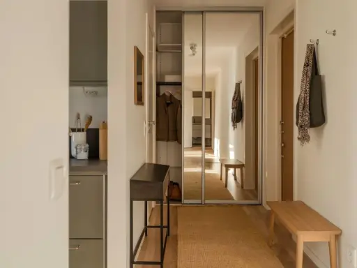 En ljus hall med spegelskjutdörrar, en smal konsol och en träbänk. Perfekt hall inspiration för en funktionell och stilren entré.