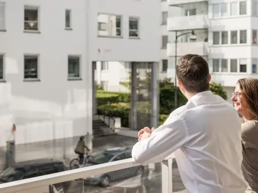 Ett par njuter av utsikten från sin balkong, kanske funderar på framtida medlemsinsatser brf.