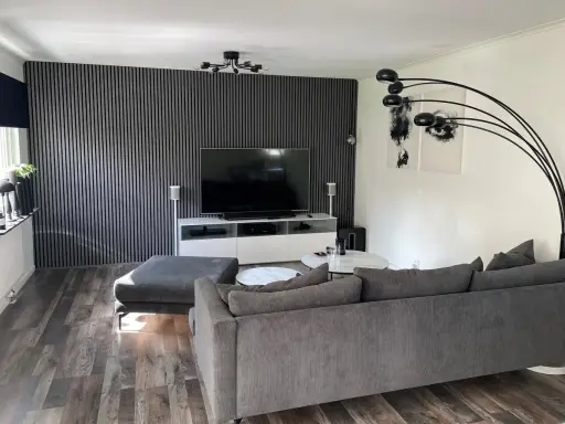Modernt tvrum med ribbvägg och grå soffa. Perfekt tvrum inspiration för dig som gillar stilrent och avskalat.