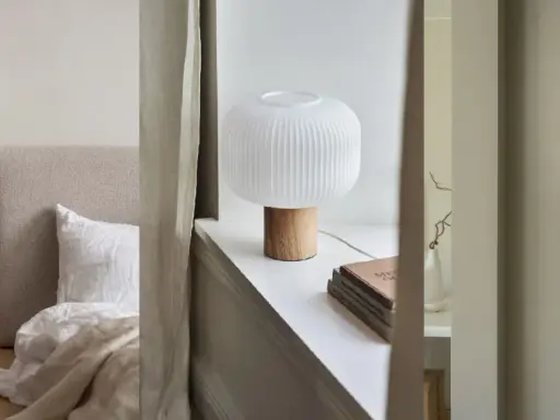 Sovrumsinspiration med en taklampa i papper, en bordslampa med träfot och en vägglampa som liknar ett skal.
