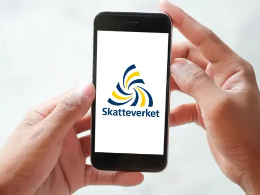 Händer håller en mobil med Skatteverkets logotyp. Enkel hantering av fastighetsskatt deklaration.