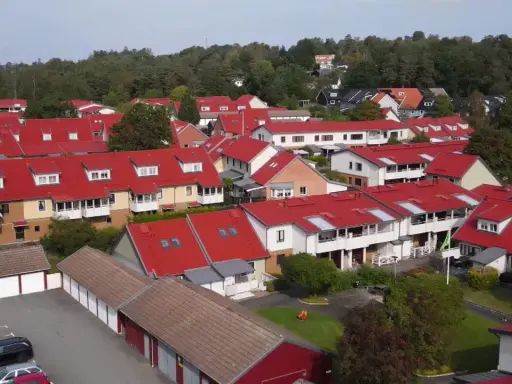 Radhusområde med röda tak i Sverige. Tänk på att fastighetsskatt för brf kan påverka boendekostnaderna.