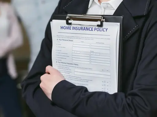 Person håller ett dokument med rubriken "HOME INSURANCE POLICY". Detta kan vara en del av ett hyresavtal lokal.