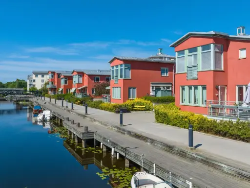 Radhus vid vattnet med båtar i hamnen. En extern styrelse för brf kan diskutera kostnad för underhåll av bryggan.