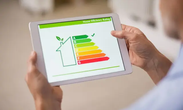 En person håller en surfplatta som visar en energideklaration för en bostadsrättsförening (brf) med en skala från A till G.