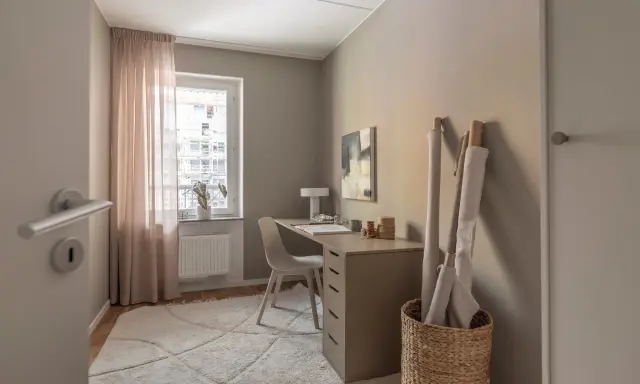 Mysigt hemmakontor med skrivbord, stol, lampa och tygrullar. Perfekt hemmakontor inspiration för kreativa själar.