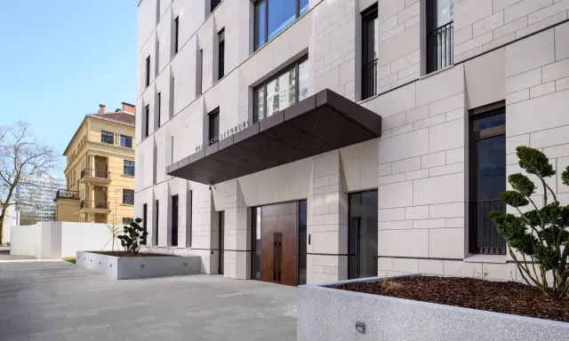 Modern villa med stenfasad och dubbeldörrar. En skylt visar "VILLA SCHELLENBURG". Kanske en symbol för en brf konkurs?