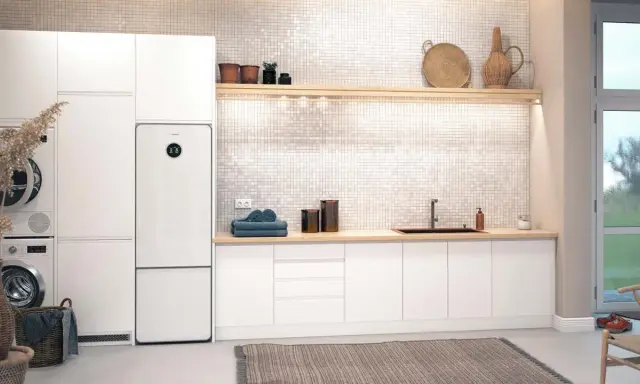 Vit tvättstuga med Bosch Compress 7800i värmepump, tvättmaskin, torktumlare och en bänkskiva med diskho.