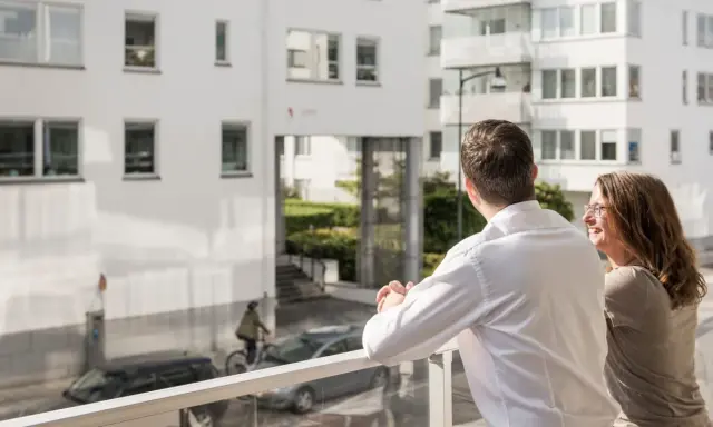 Ett par njuter av utsikten från sin balkong, kanske funderar på framtida medlemsinsatser brf.