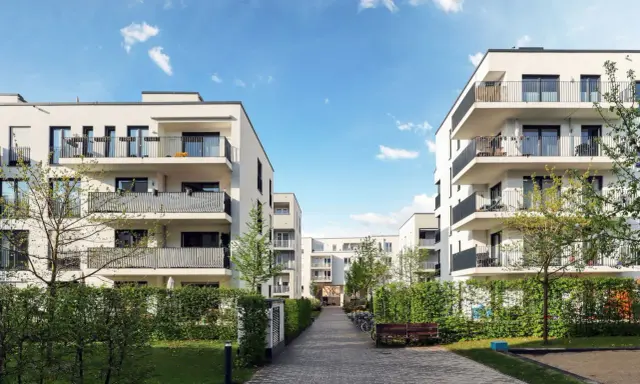 Moderna bostadshus med balkonger och grönska. En lugn innergård med gångväg, bänk och cyklar. Perfekt för en trygg boendemiljö, som en revisor brf skulle uppskatta.