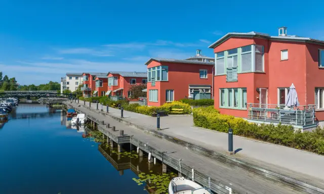 Radhus vid vattnet med båtar i hamnen. En extern styrelse för brf kan diskutera kostnad för underhåll av bryggan.