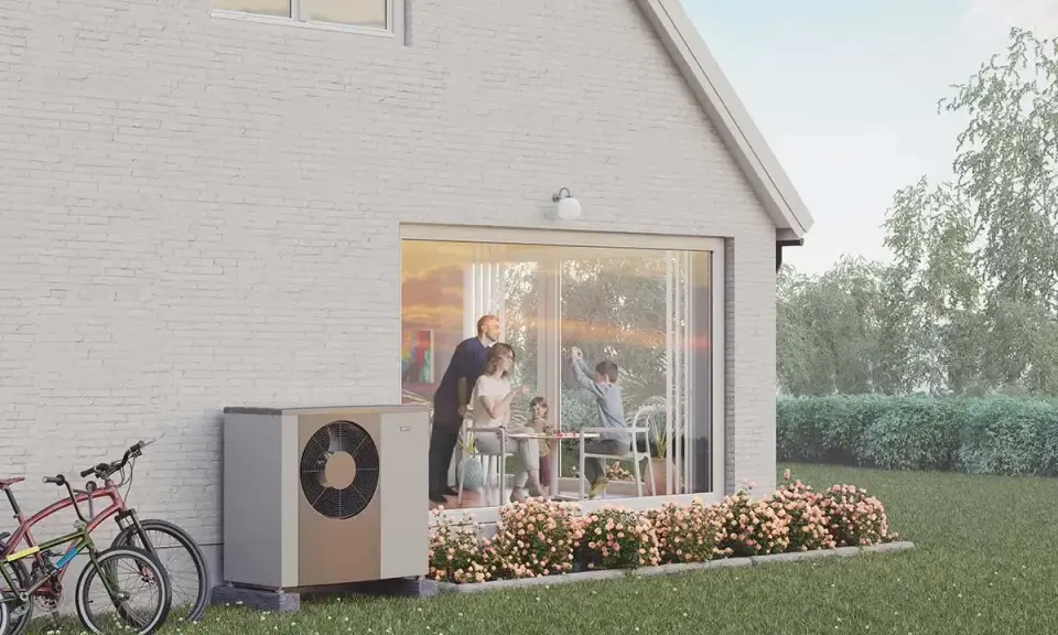 En familj njuter av en solig dag vid sitt hus, med en NIBE S2125-12 värmepump som diskret står vid sidan.