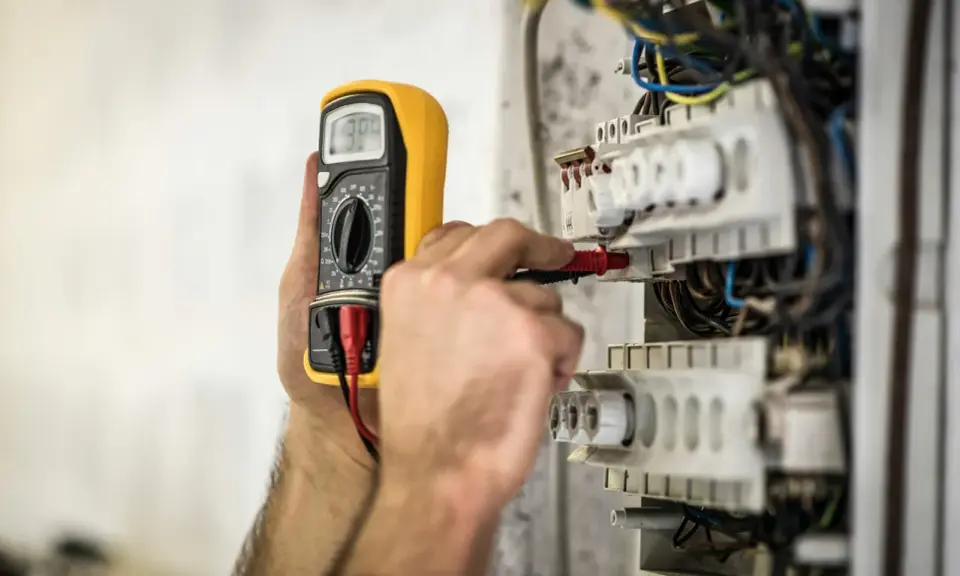 En elektriker använder en multimeter för att kontrollera elsystemet. Detta är en del av elbesiktning krav för säkerhet.