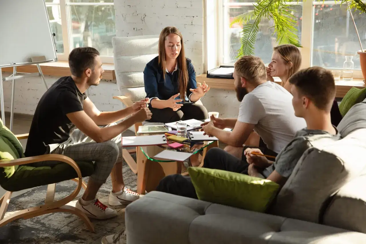 Grupp diskuterar brf styrelse roller. En kvinna leder m&ouml;tet, medan andra lyssnar och antecknar.